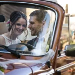 Glückliches Brautpaar im Vintage Hochzeitsauto – Stilvolle Hochzeitsfotografie NOVA Wien