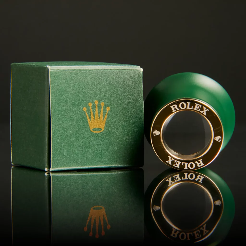 Produktfotografie Wien – grüne Patek Philippe Lupe mit Originalverpackung auf schwarzem Hintergrund