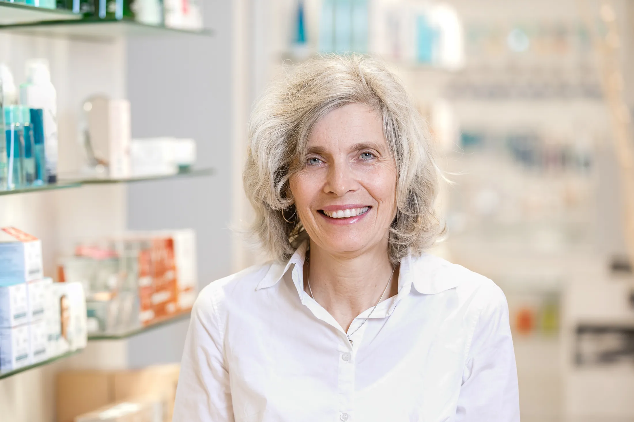 Freundliche Apothekerin im weißen Kittel in der Apotheke – Medizinische Business-Fotografie NOVA Wien