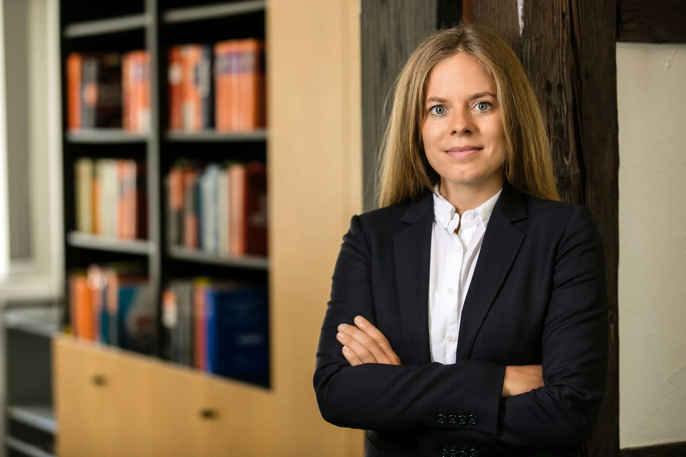 businessfoto-wien-rechtsanwalt-steuerberater Frau mit langen blonden Haaren im Büro an die Zür gelehnt | NOVA Fotografie