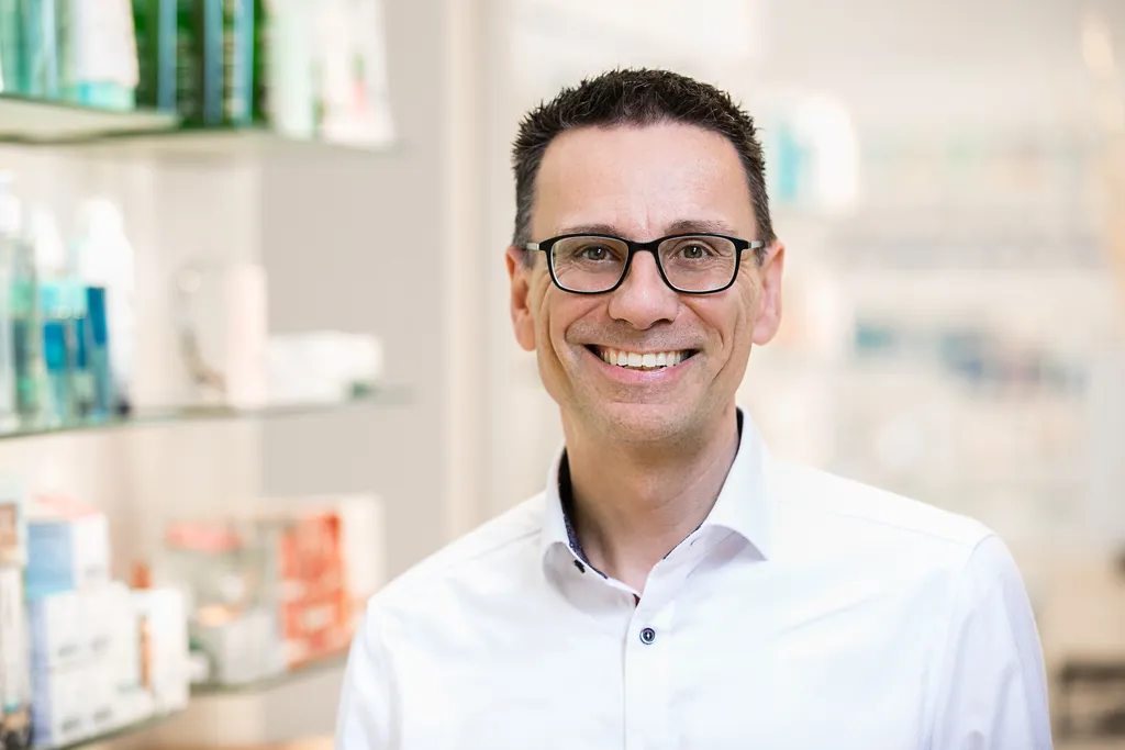 Freundlicher Apotheker im weißen Kittel in der Apotheke – Medizinische Business-Fotografie NOVA Wien