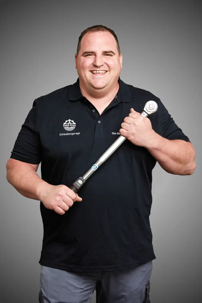 Lachender Mechaniker präsentiert einen großen Drehmomentschlüssel – Business Portrait für Handwerker und Unternehmer Wien
