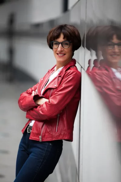 Selbstbewusste Geschäftsfrau in roter Lederjacke mit Spiegelung – Moderne Business-Fotografie NOVA Wien
